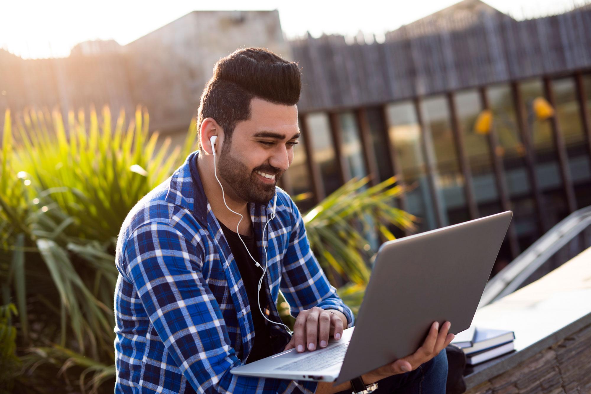 Business student outside working on a laptop